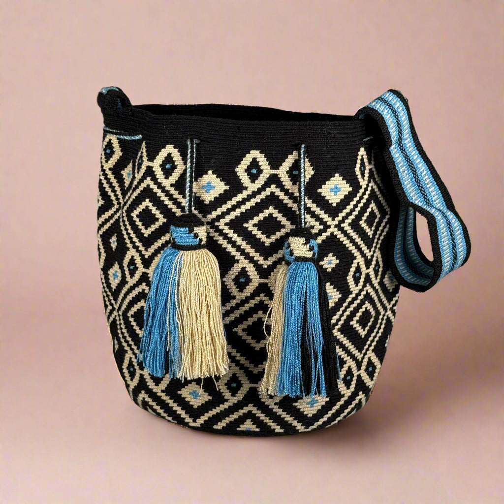 Black bag with geometric pattern and blue tassels on a light gray background